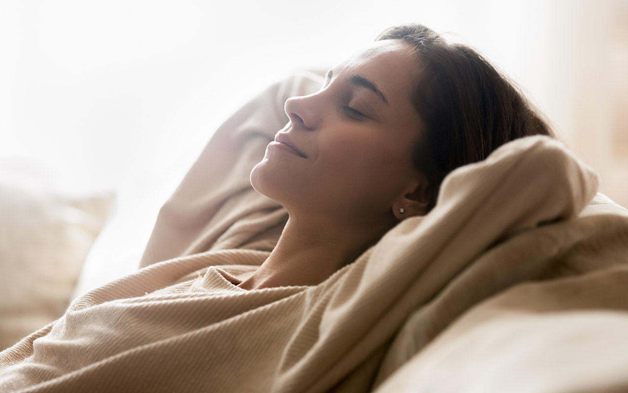 Happy young woman relaxing on comfortable sofa at home